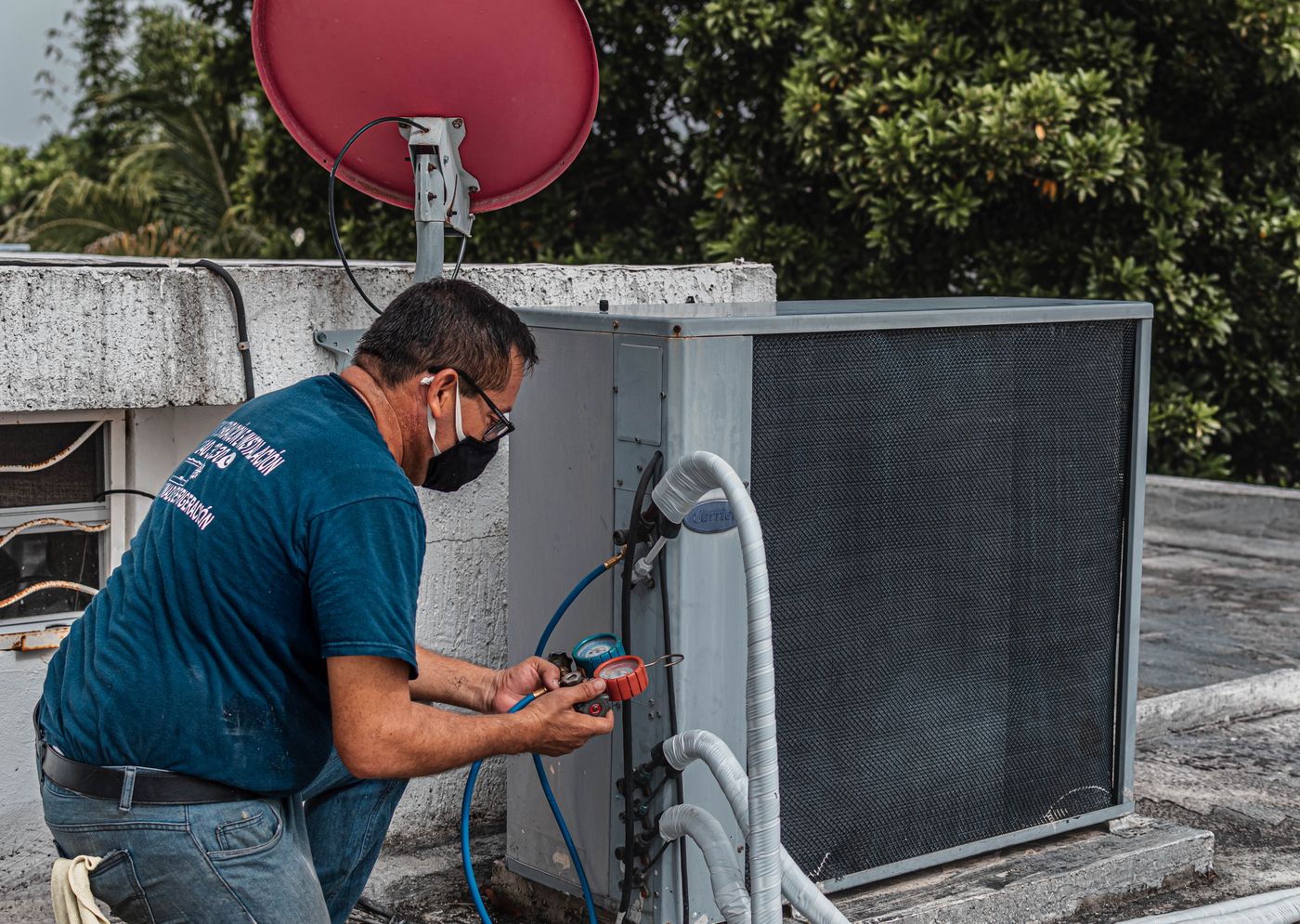 Técnico fazendo manutenção em condensadora com ferramentas e manifold
